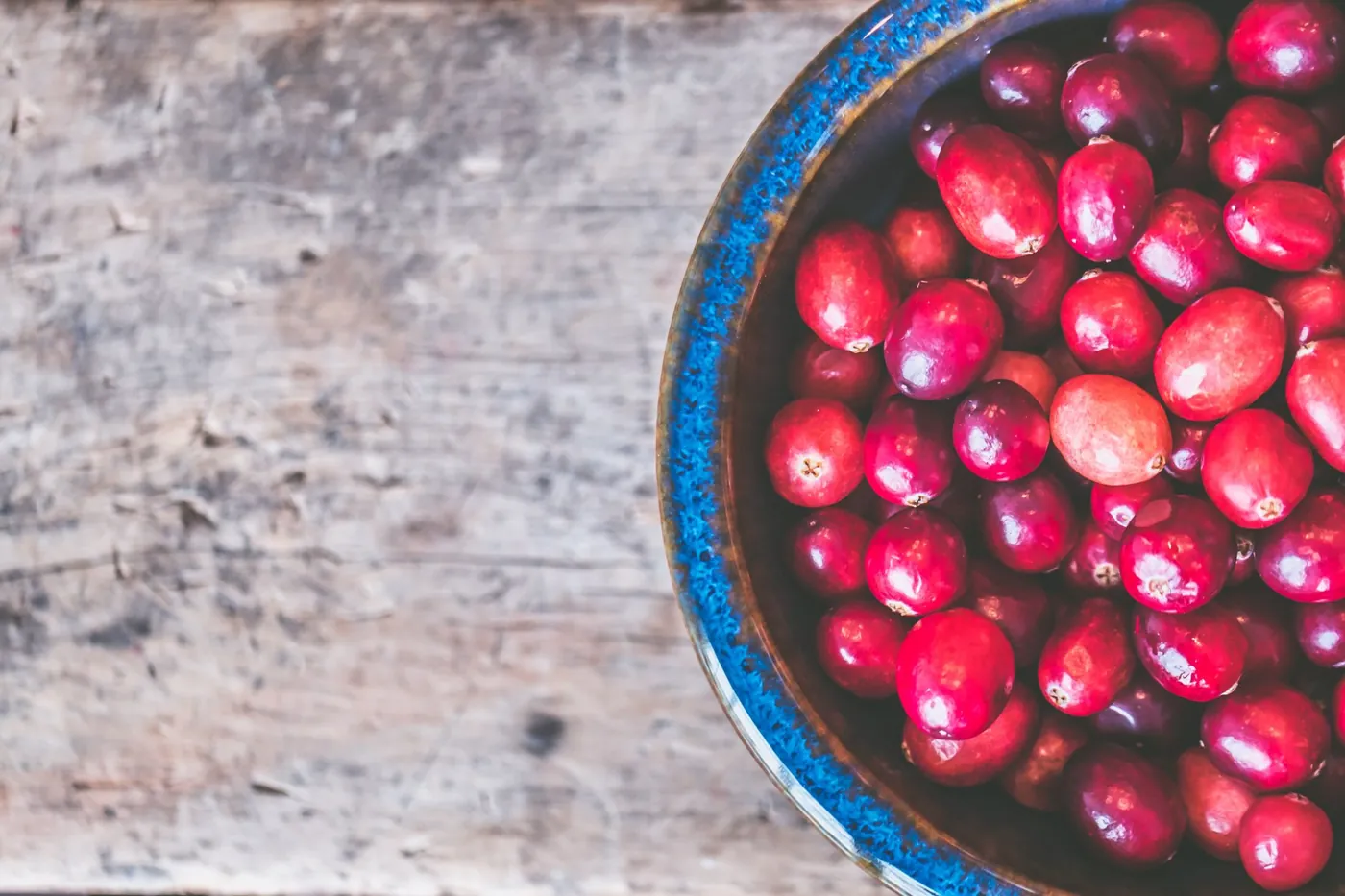 Fresh cranberries in a bowl on a wooden table