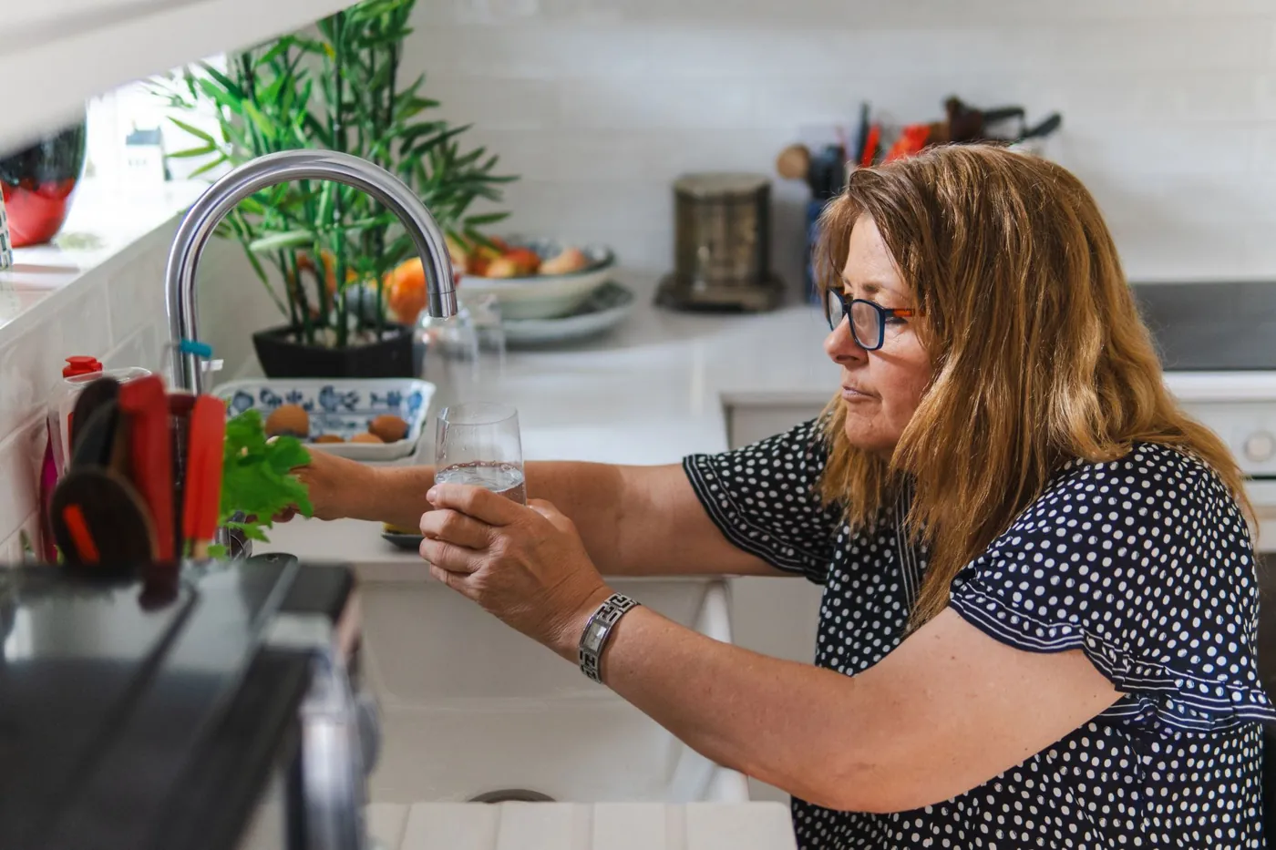 Middle aged woman filling a glass of water in her kitchen