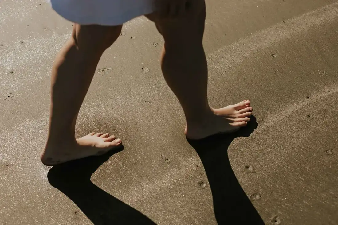 Bare feet walking on wet sand in the sun