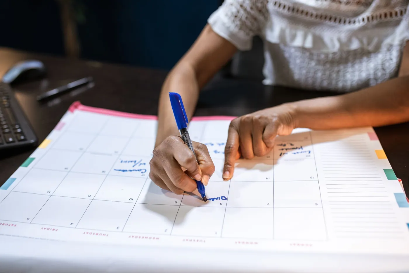 Woman marking a date on a desk calendar