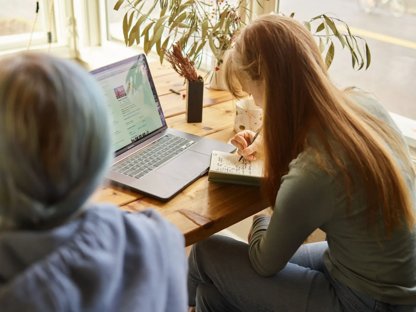 Woman working through notes beside a laptop